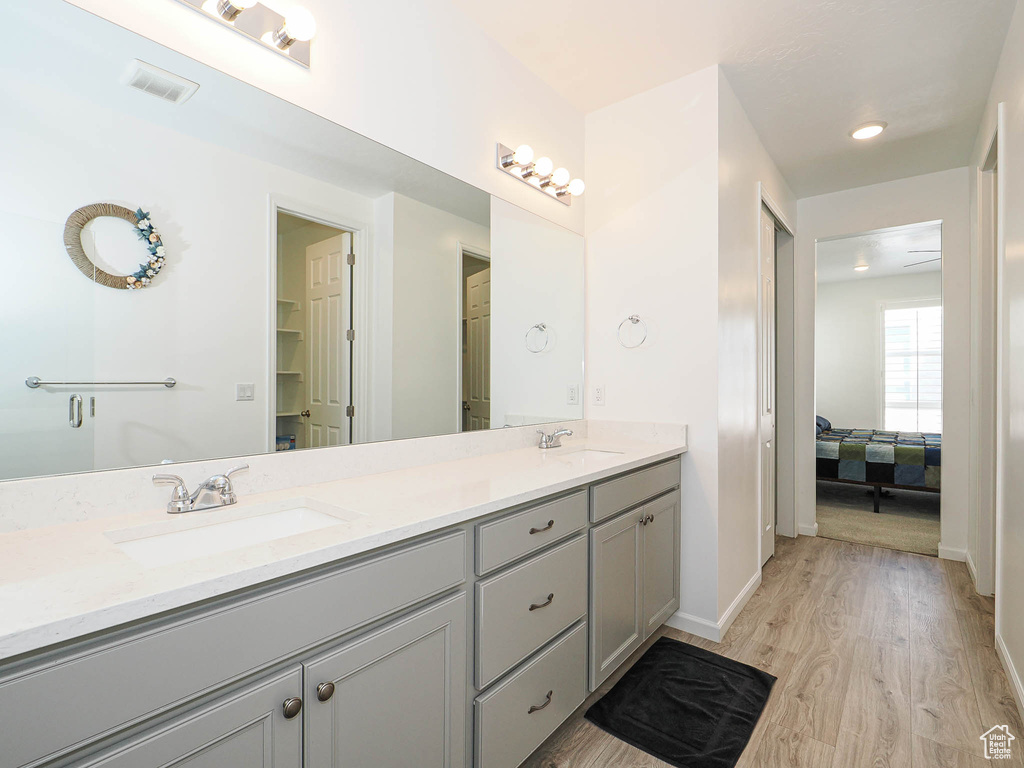 Ensuite bathroom featuring double vanity and wood finished floors