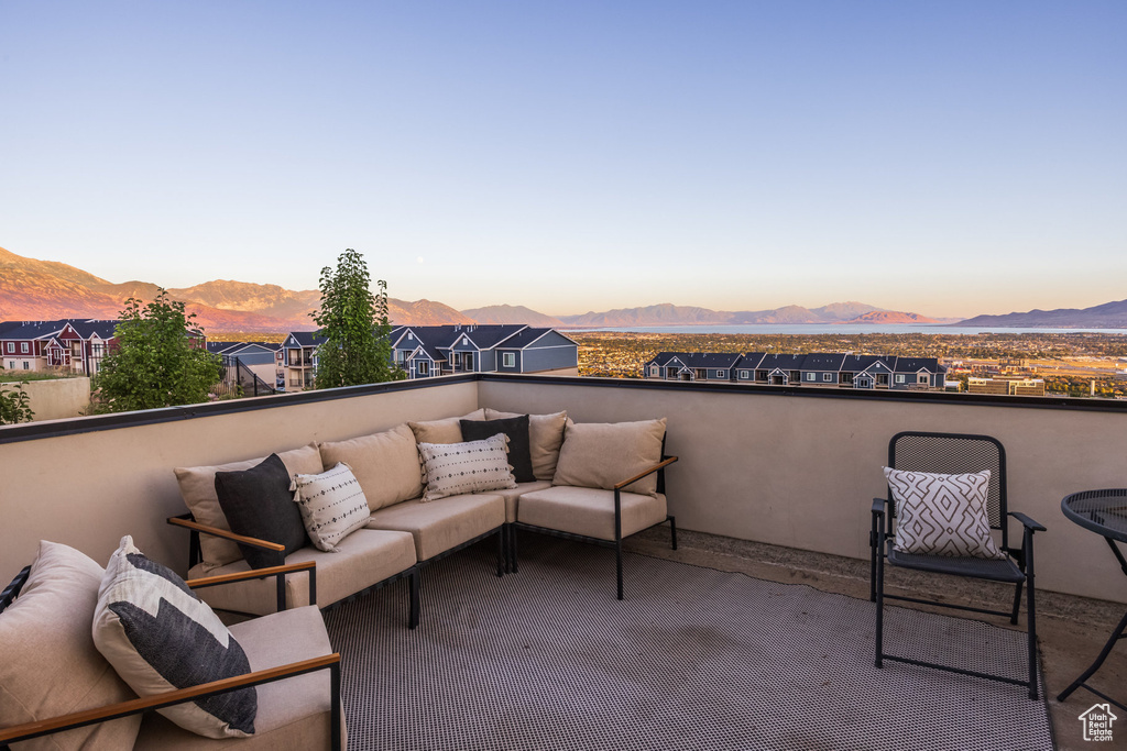 Patio terrace at dusk with outdoor lounge area, a mountain view, and a balcony