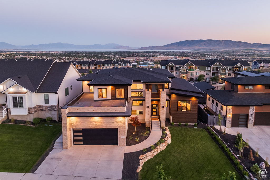View of front of property with concrete driveway, a mountain view, an attached garage, a residential view, and a front lawn