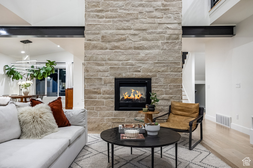 Living area featuring wood finished floors, a brick fireplace, and stairs