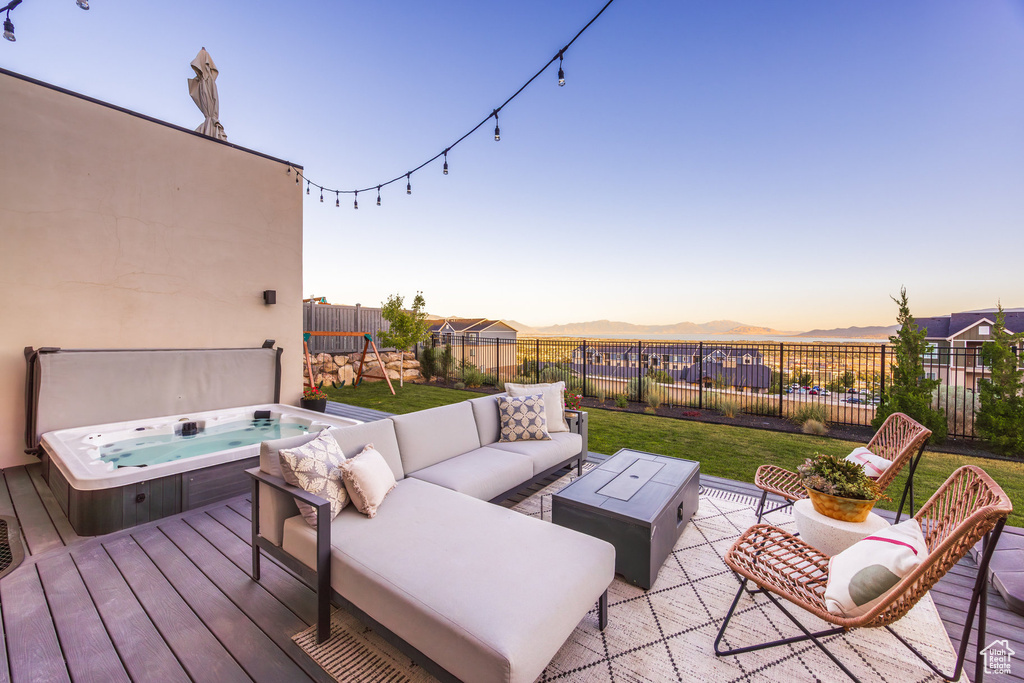 Wooden terrace with a covered hot tub, a fenced backyard, outdoor lounge area, and a mountain view