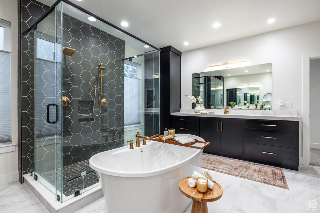 Bathroom with marble finish floors, a freestanding bath, a stall shower, recessed lighting, and vanity