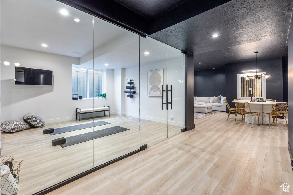 Exercise room featuring wood finished floors, recessed lighting, and a chandelier