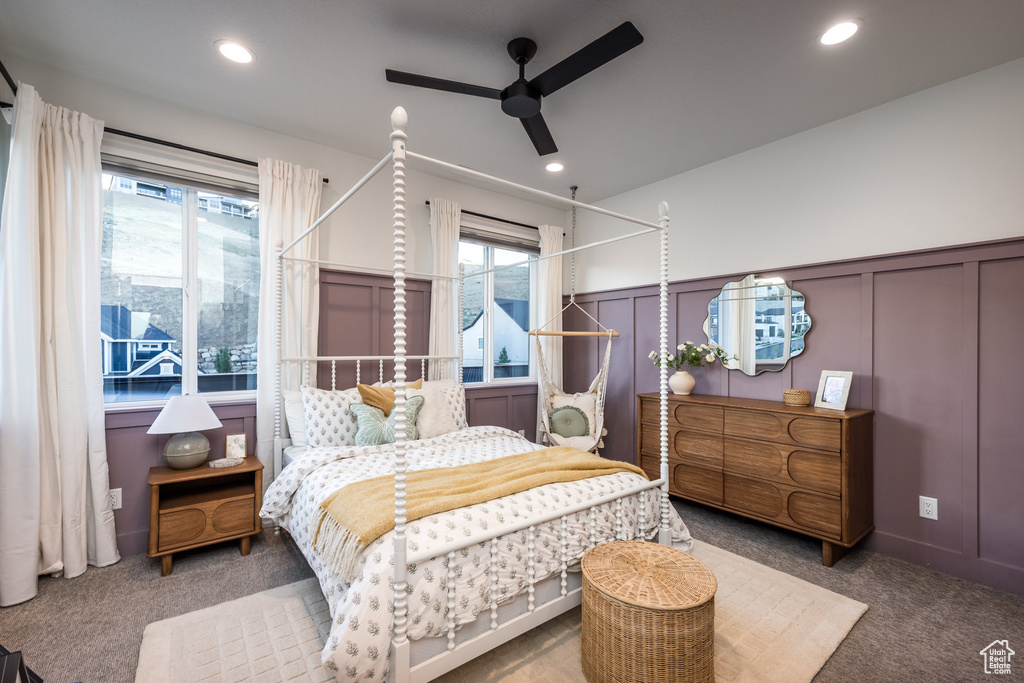 Bedroom with carpet flooring, a decorative wall, multiple windows, wainscoting, and recessed lighting