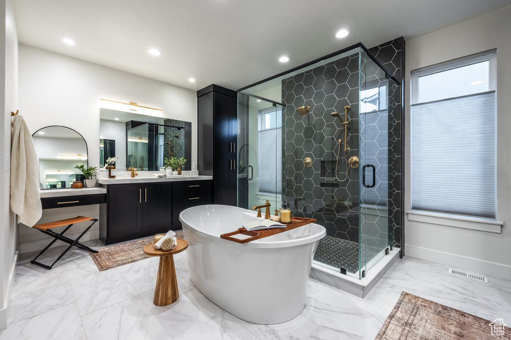 Bathroom featuring a freestanding tub, marble look tiles, a shower stall, vanity, and recessed lighting