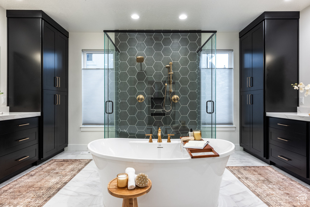 Full bath with marble look tile flooring, healthy amount of natural light, vanity, and recessed lighting
