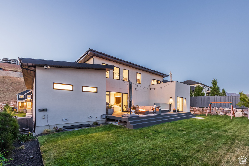 Rear view of property with an outdoor living space, a deck, and stucco siding