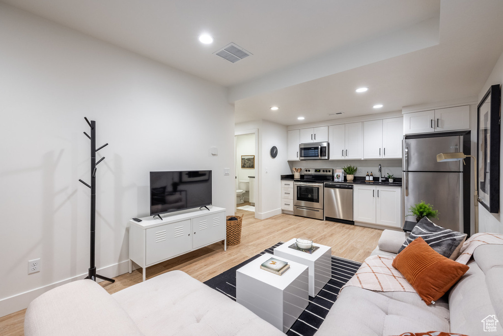 Living area with recessed lighting, light wood-type flooring, and bar
