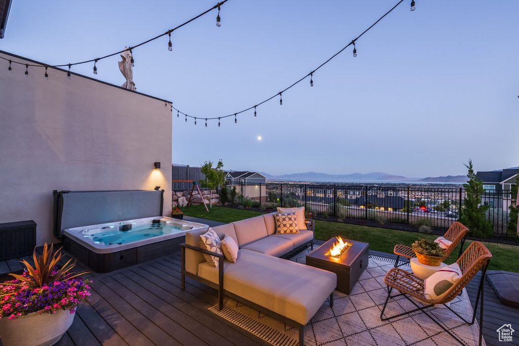 Deck with a fire pit, a mountain view, a fenced backyard, and a patio