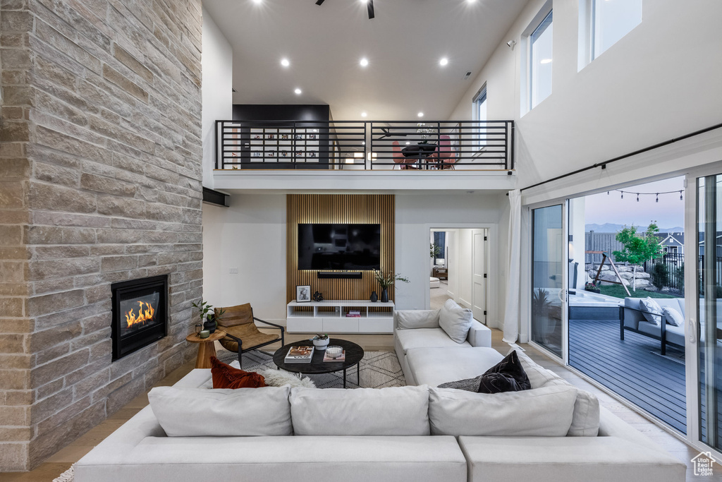 Living area featuring a fireplace, a towering ceiling, recessed lighting, and wood finished floors