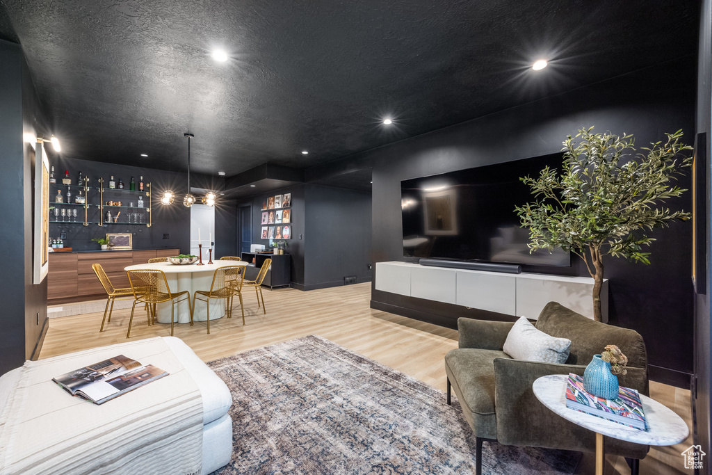 Living area with wood finished floors, recessed lighting, and bar
