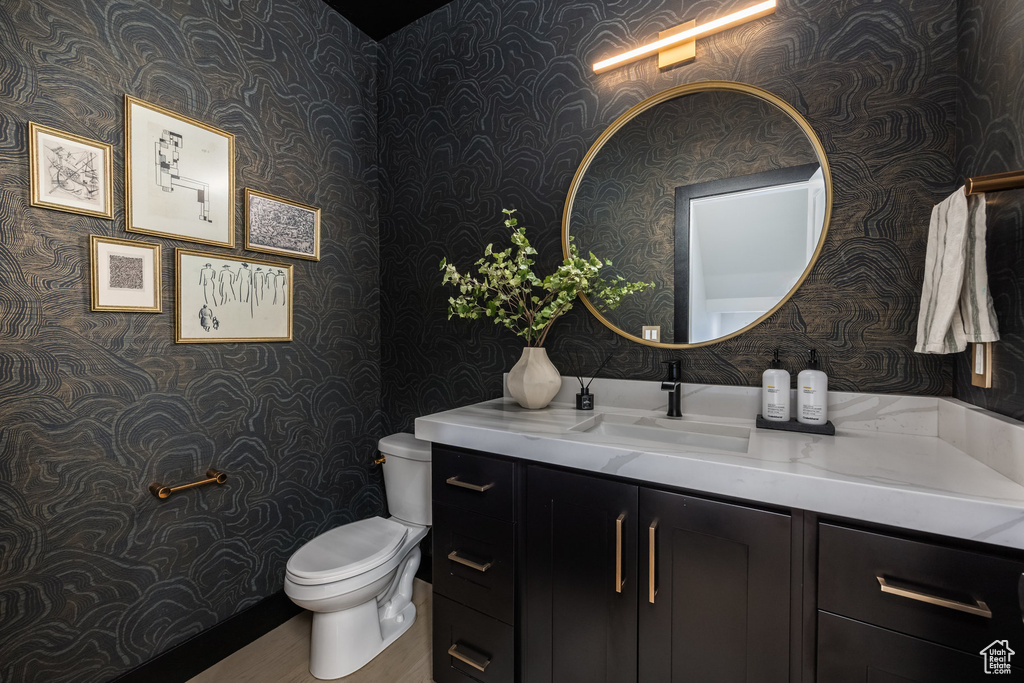 Bathroom featuring wallpapered walls, vanity, and wood finished floors