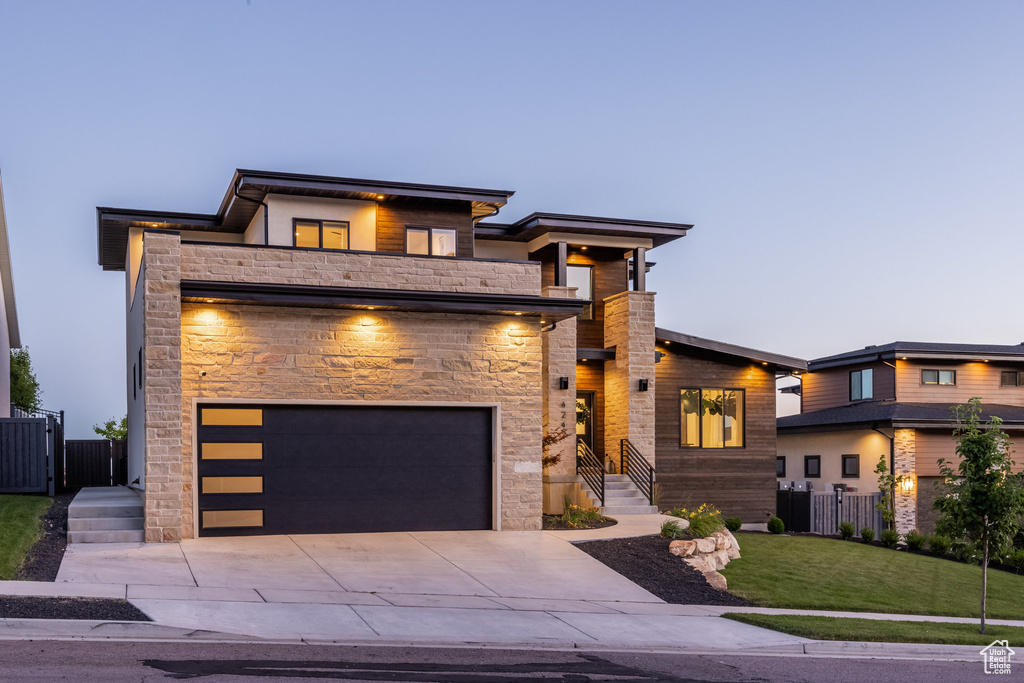Modern home featuring stone siding, driveway, and an attached garage