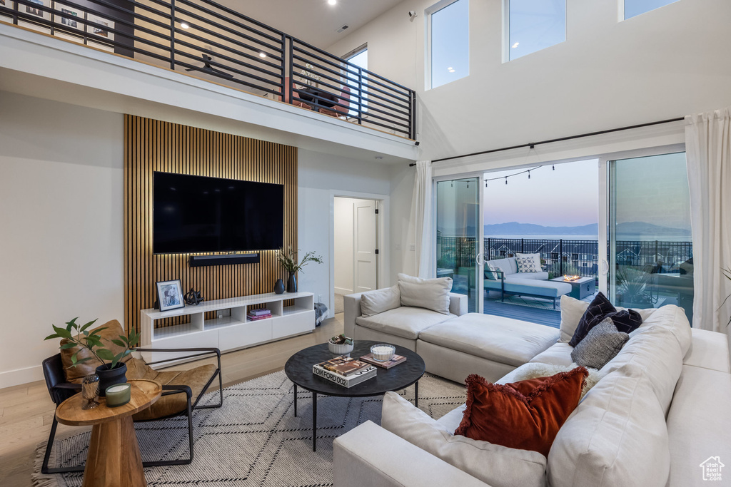 Living room with wood finished floors, a towering ceiling, and recessed lighting