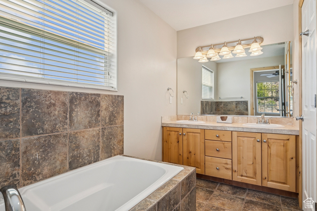 Bathroom with a bath, double vanity, stone finish floors, and a ceiling fan