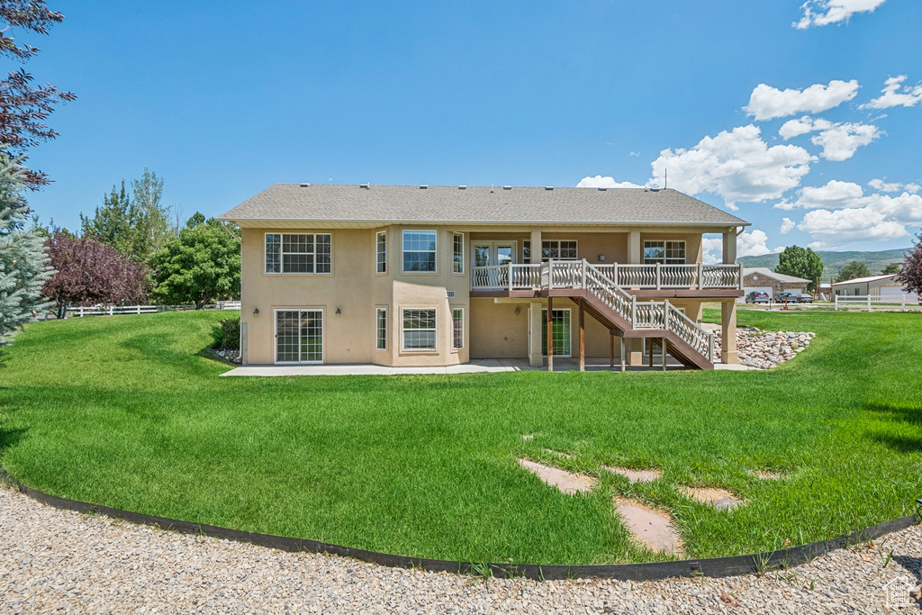 Rear view of property featuring stucco siding, stairway, a patio area, and a wooden deck