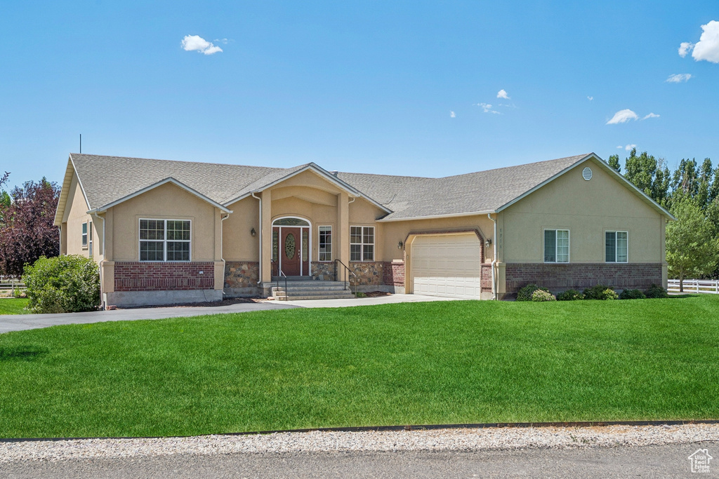 Ranch-style house with stucco siding, an attached garage, concrete driveway, and brick siding