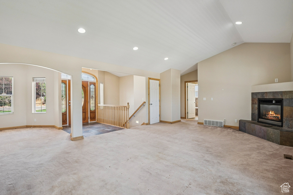 Unfurnished living room featuring carpet floors, vaulted ceiling, recessed lighting, and a tiled fireplace