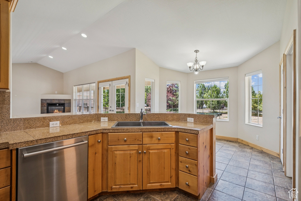 Kitchen featuring stainless steel dishwasher, tile counters, a chandelier, a tiled fireplace, and pendant lighting