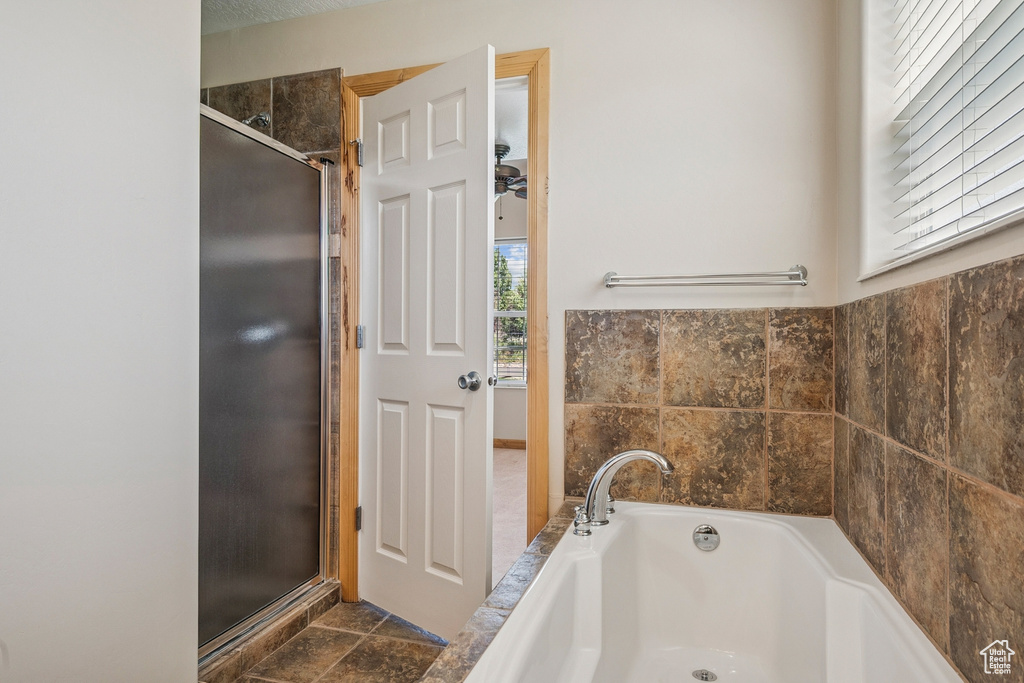Full bath with a garden tub, a shower stall, and stone finish flooring