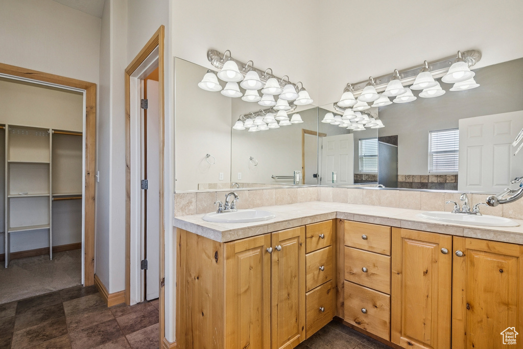 Bathroom featuring double vanity, a spacious closet, and a shower