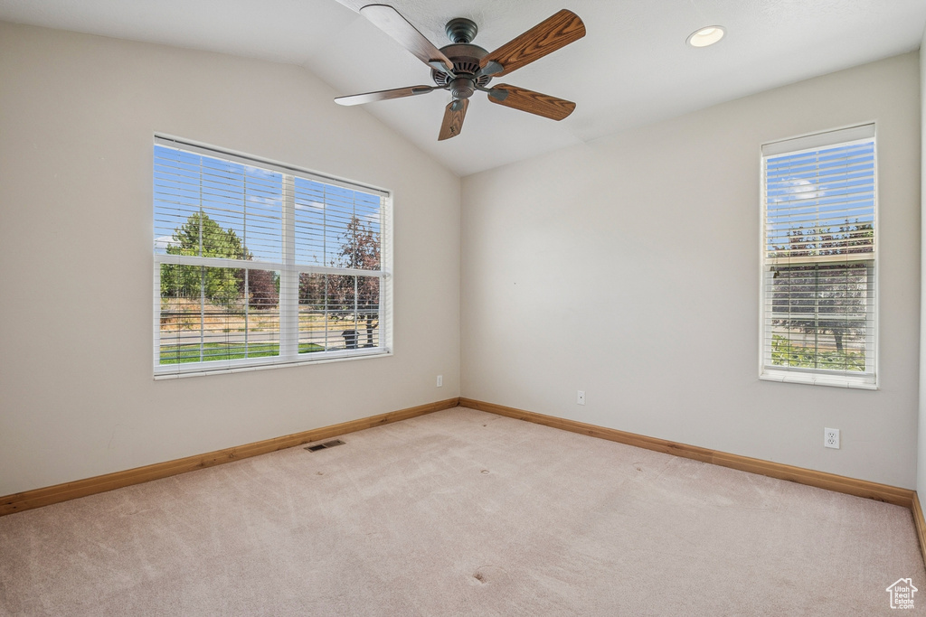 Unfurnished room with plenty of natural light, light colored carpet, ceiling fan, vaulted ceiling, and recessed lighting