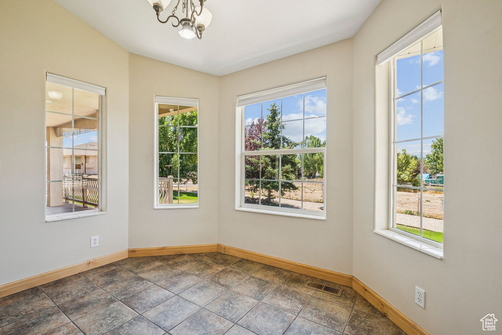 Empty room featuring a chandelier and dark stone finish floors
