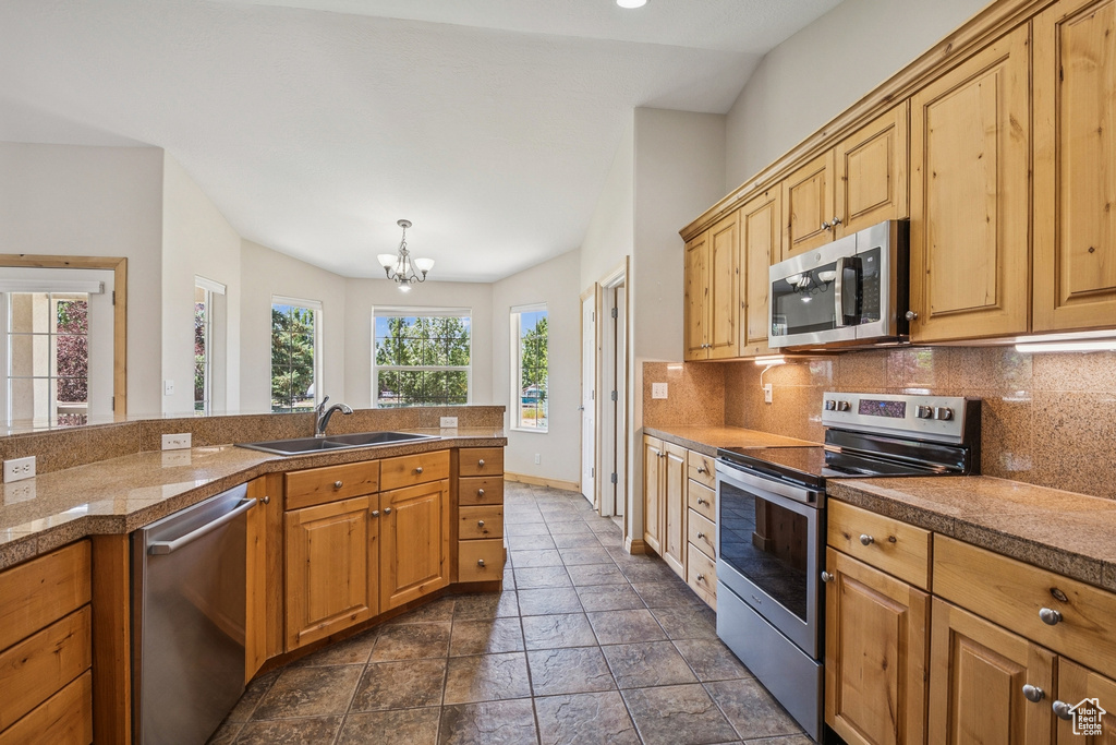 Kitchen featuring stainless steel appliances, backsplash, a chandelier, tile countertops, and dark stone finish flooring