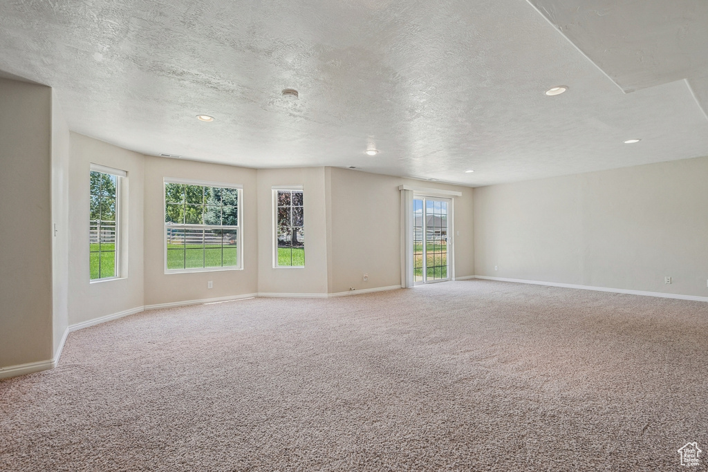 Unfurnished room with carpet flooring, a textured ceiling, recessed lighting, and healthy amount of natural light