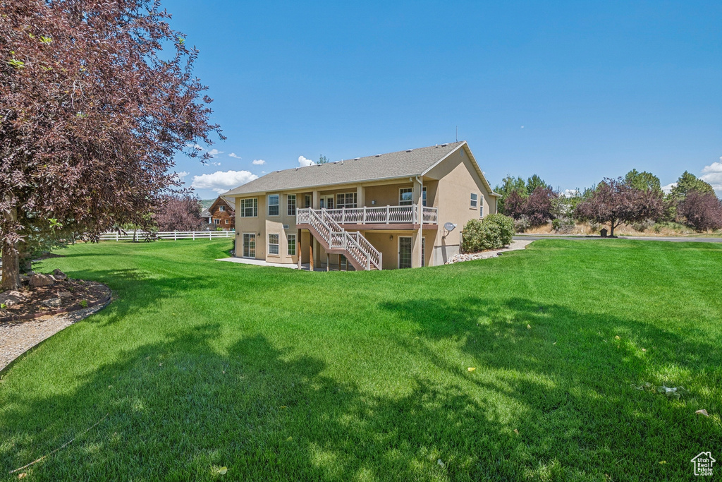 Back of property featuring stucco siding, stairs, and a wooden deck