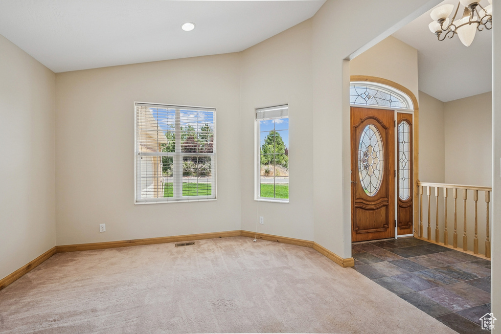 Entryway with plenty of natural light, a chandelier, carpet, and high vaulted ceiling
