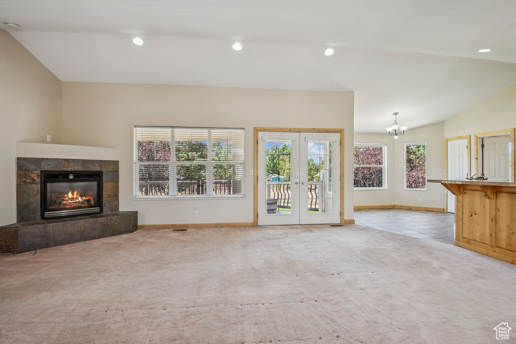Unfurnished living room with carpet flooring, a chandelier, a fireplace, french doors, and recessed lighting