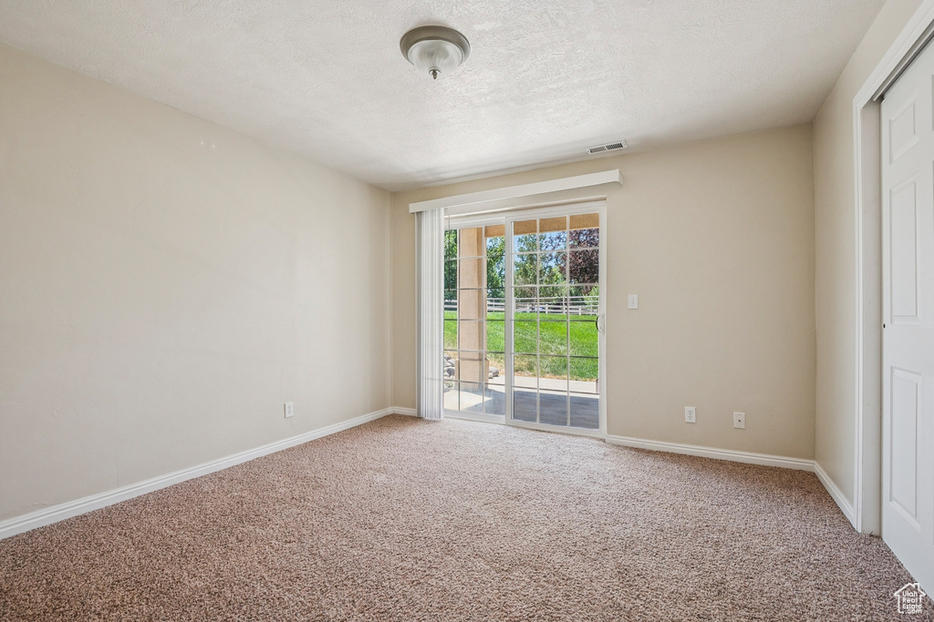 Carpeted empty room featuring a textured ceiling and baseboards