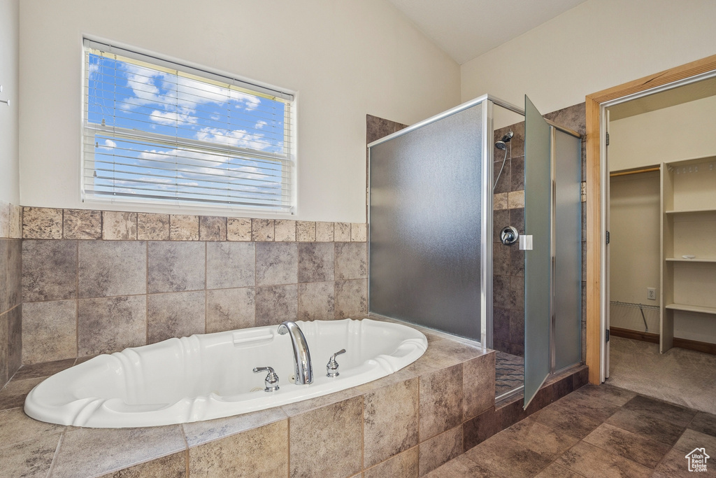 Full bathroom featuring a shower stall, a bath, and a walk in closet
