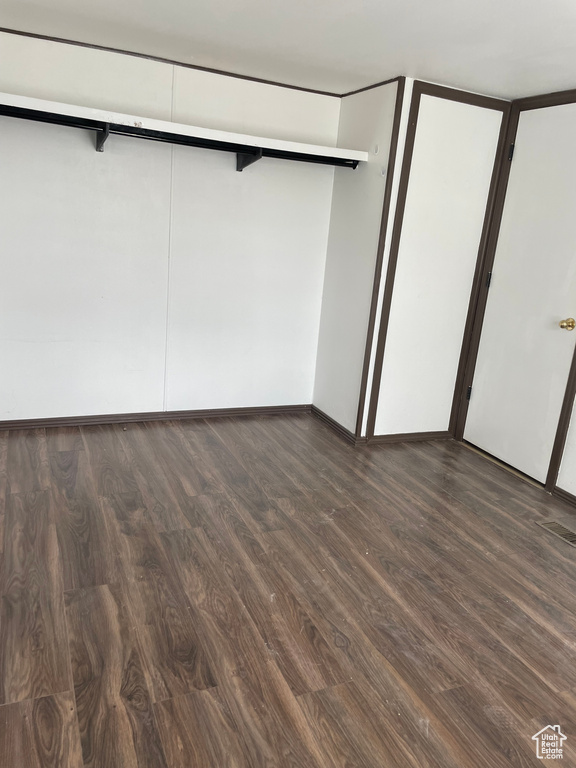 Unfurnished bedroom featuring dark wood-type flooring and a closet