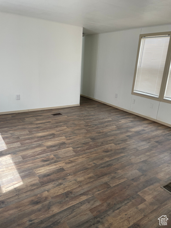 Empty room featuring dark wood finished floors and baseboards