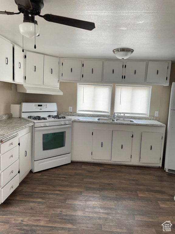 Kitchen featuring white appliances, under cabinet range hood, white cabinets, and a textured ceiling