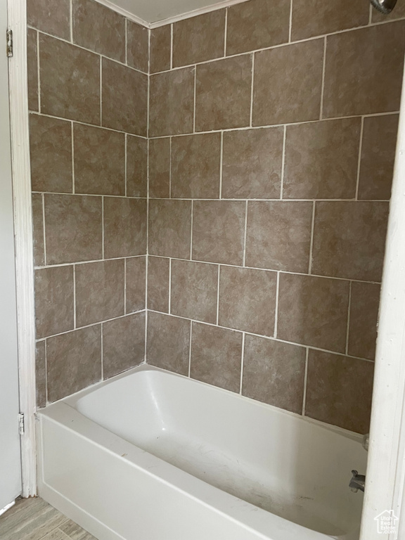 Bathroom featuring washtub / shower combination and wood finished floors