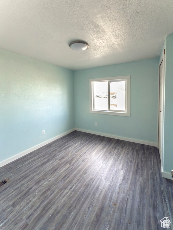 Unfurnished bedroom featuring dark wood-style flooring and a textured ceiling