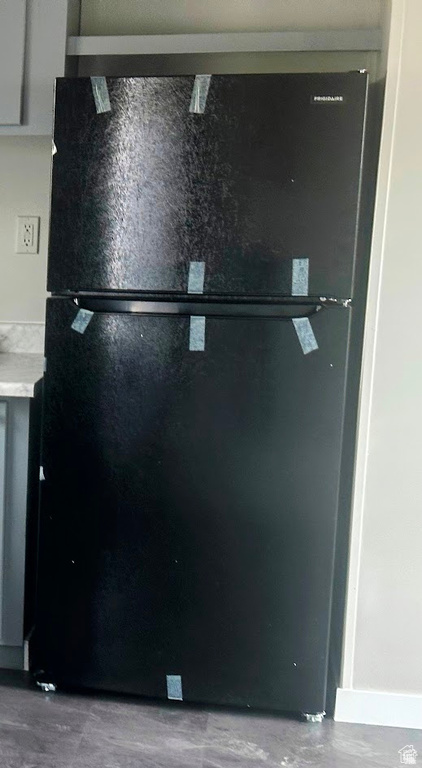 Kitchen view of freestanding refrigerator, light countertops, and concrete floors