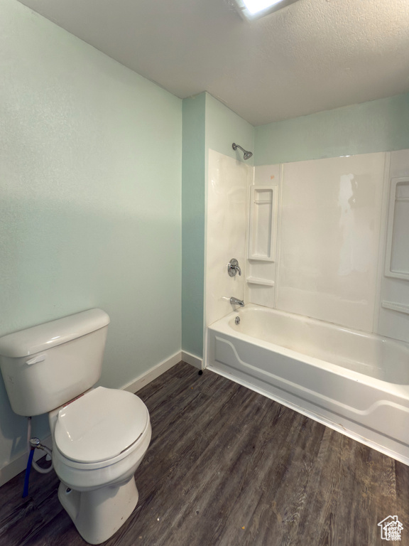Bathroom with wood finished floors,  shower combination, and a textured ceiling