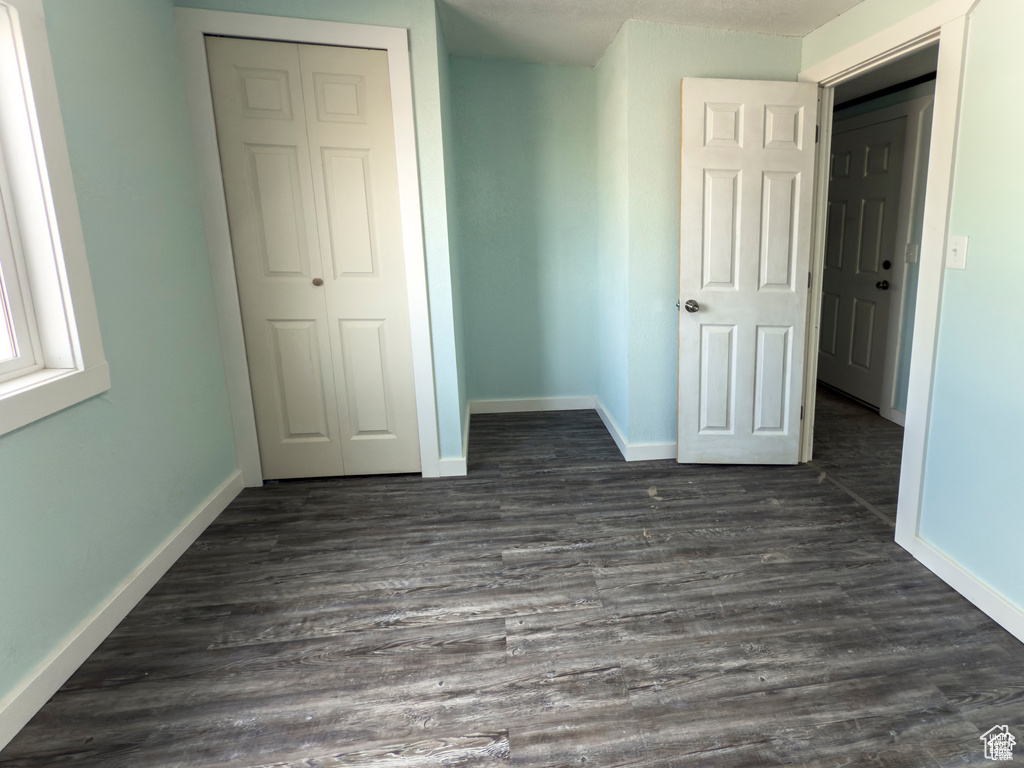 Unfurnished bedroom with a closet and dark wood finished floors