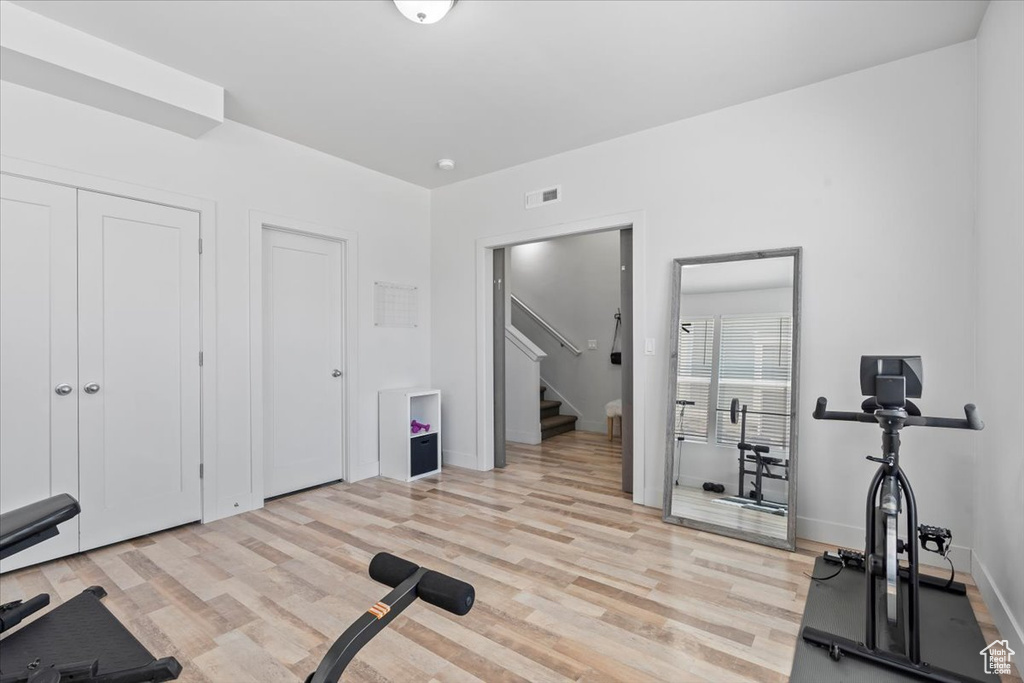 Exercise room with light wood-style floors and baseboards