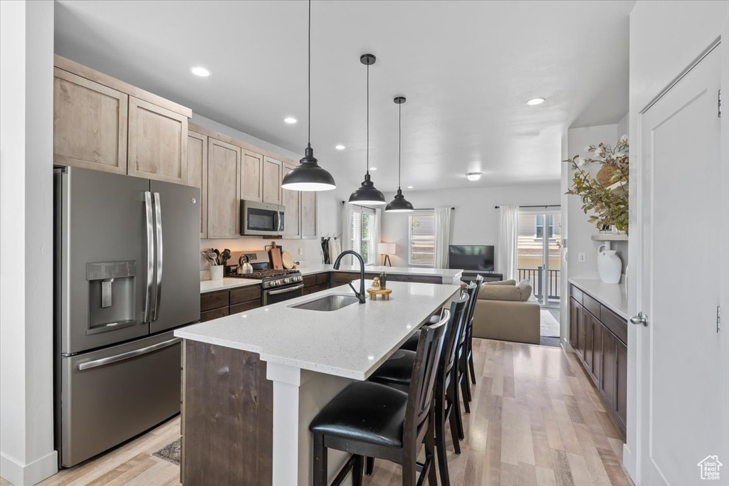 Kitchen featuring appliances with stainless steel finishes, light wood-style floors, open floor plan, light brown cabinets, and recessed lighting