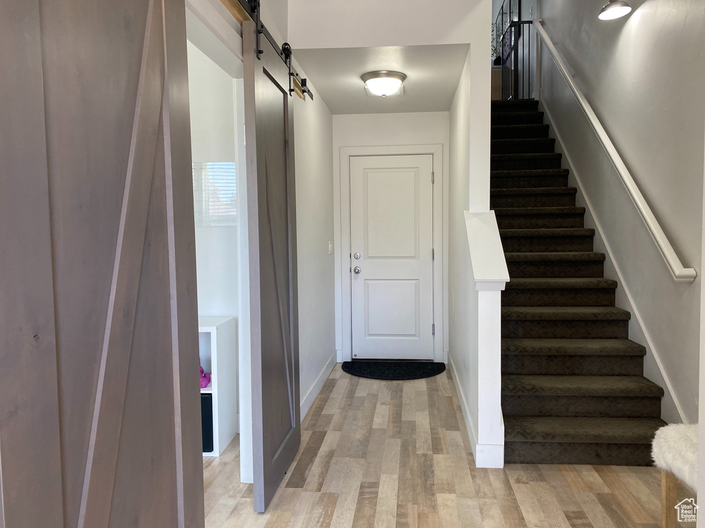 Stairs featuring a barn door and wood finished floors