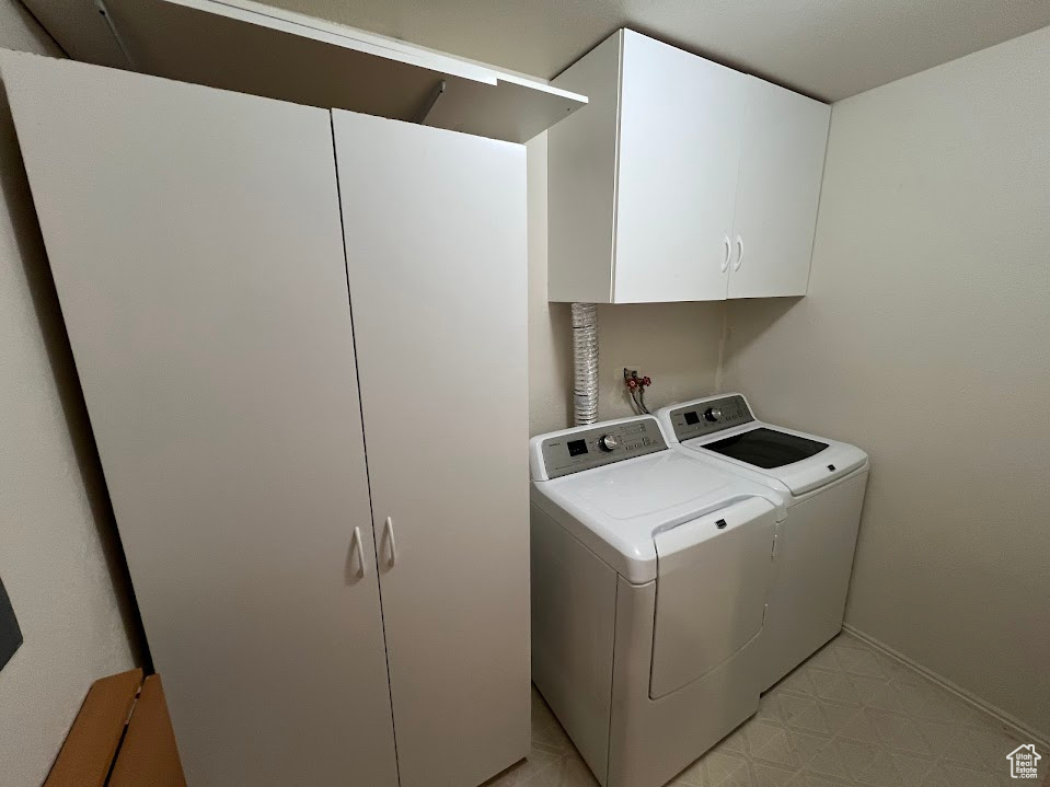 Laundry area featuring cabinet space, separate washer and dryer, and light floors