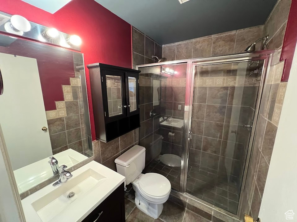 Full bath with tile walls, vanity, and a stall shower