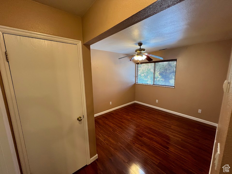 Unfurnished bedroom with dark wood-style flooring, a ceiling fan, and a closet