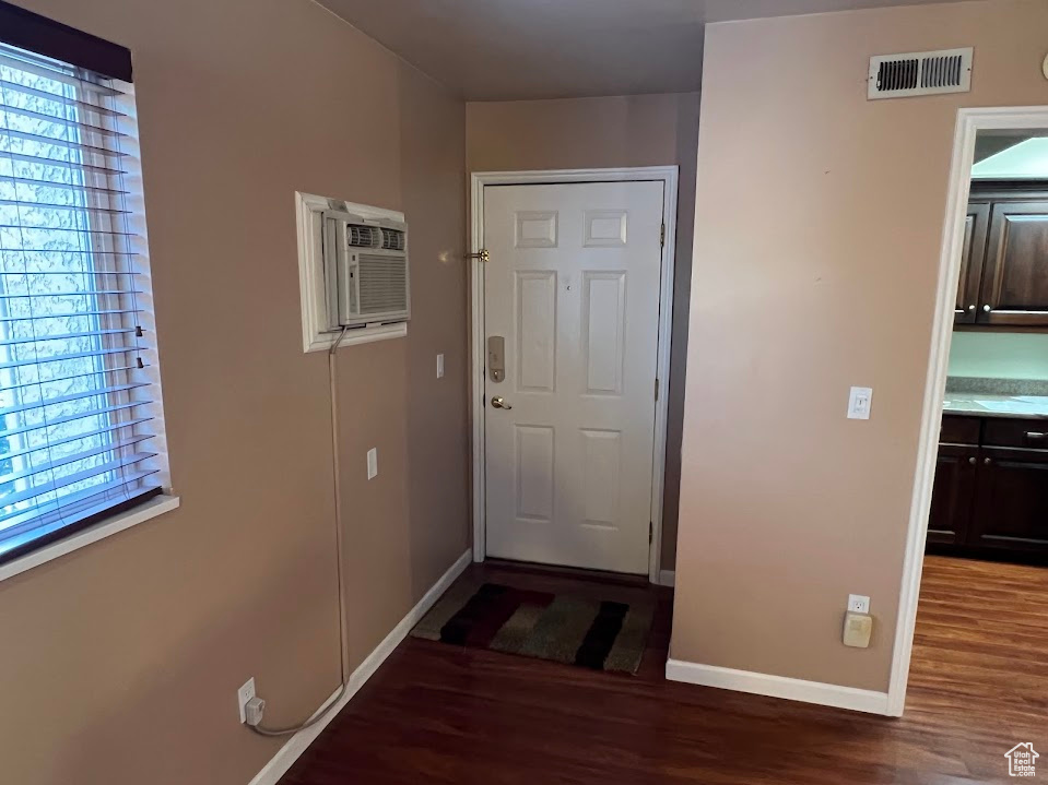 Doorway with an AC wall unit and wood finished floors