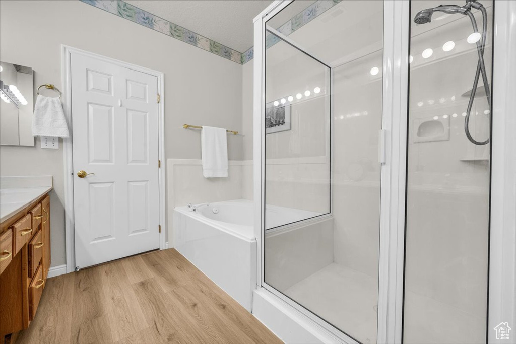 Full bath featuring vanity, wood finished floors, a shower stall, and a garden tub